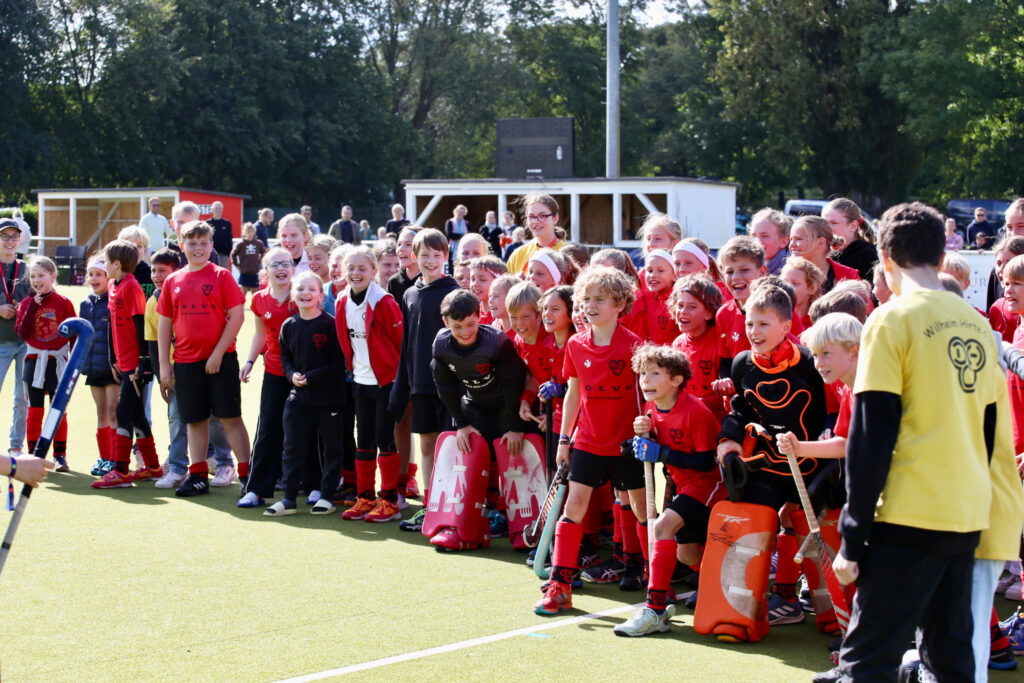 Kinder stehen aufgereiht auf dem Hockeyplatz und jubeln
