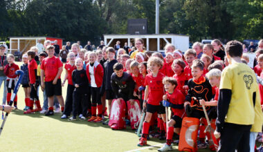 Kinder stehen aufgereiht auf dem Hockeyplatz und jubeln