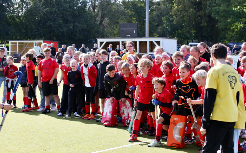 Kinder stehen aufgereiht auf dem Hockeyplatz und jubeln